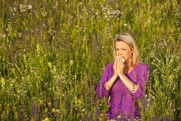 Attraktive Frau auf einem Blumenfeld mit allergischen Symptomen — Stockfoto