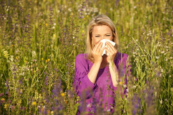 Aantrekkelijke vrouw in een veld van de bloem met allergische symptomen — Stockfoto