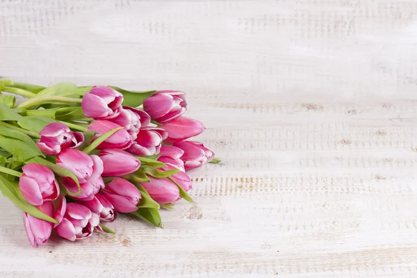 Ramo de tulipanes rosados en una tabla de madera — Foto de Stock