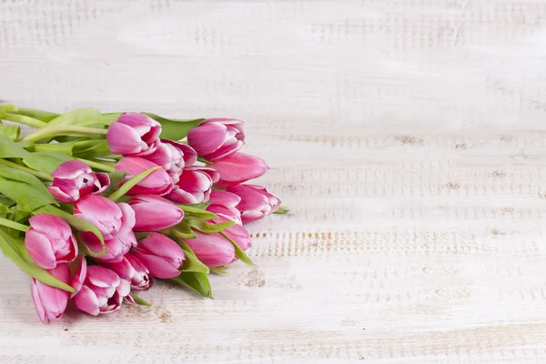 Um monte de tulipas cor-de-rosa numa tábua de madeira — Fotografia de Stock