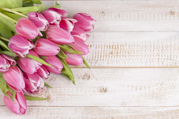 Bos van roze tulpen op een houten bord — Stockfoto