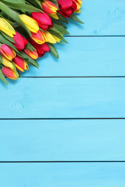 Manojo de tulipanes rojos y amarillos con fondo de madera — Foto de Stock