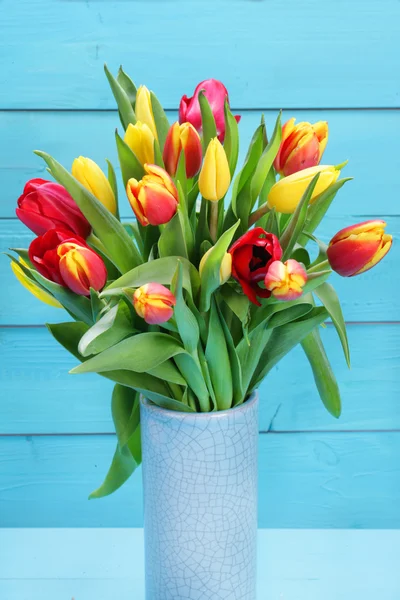 Manojo de tulipanes rojos y amarillos con fondo de madera — Foto de Stock