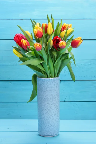 Manojo de tulipanes rojos y amarillos con fondo de madera — Foto de Stock