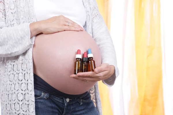 Mujer embarazada con pequeños frascos de medicina homeopática Fotos de stock
