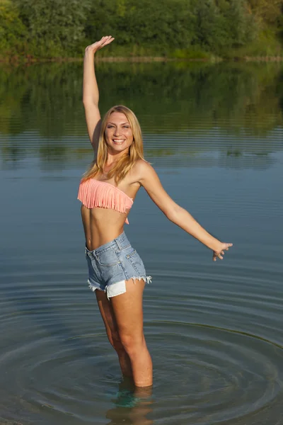 Joven mujer feliz con los brazos extendidos en un lago — Foto de Stock