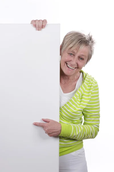 Gelukkig oudere vrouw achter een wit bord — Stockfoto