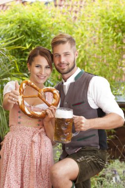 Bavarian couple in traditional costume with beer and brezel
