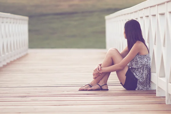 Красивая девушка сидит на мосту — стоковое фото