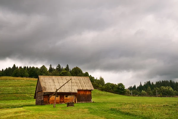 Stuga på fältet och mulen himmel — Stockfoto