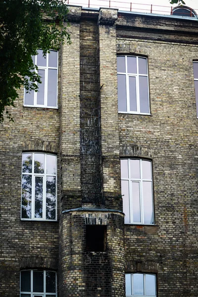 Magnificent building brick wall with plastic windows and old long chimney turned into fire escape with metal ladder
