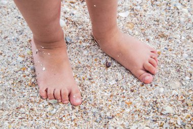 Çocukların ayakları kumsalda, güneşli, sarı kumların üzerinde duruyor.. 