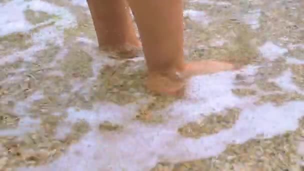 Childrens legs are standing on the sand and they are periodically. — Stock Video