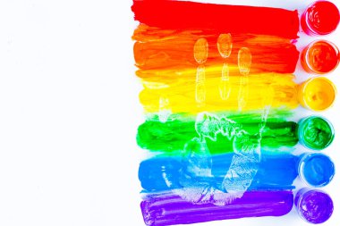 Yatay olarak çizilmiş renkli çizgiler, beyaz arka planda el izi olan gökkuşağı şeklinde boyalar. LGBT insanları. Üst görünüm, düz görünüm, kopyala boşluk, izole et.