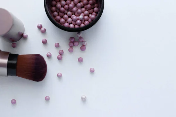 Kızaran pembe ve krem rengi toplar ve beyaz bir arka plana yazı için allık sürmek için bir fırça. Üst görünüm, düz görünüm, kopyala boşluk, izole et