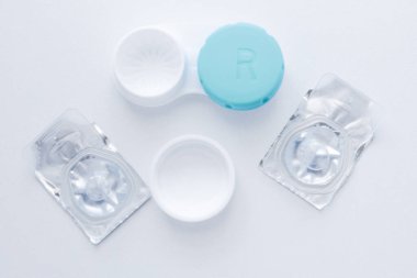 Mercek kabı ve iki mühürlü lens beyaz arka planda ortada duruyor. Üst görünüm, düz görünüm, kopyala boşluk, izole et