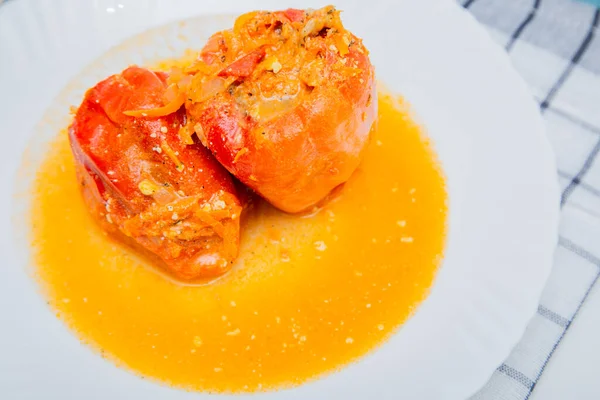 Poivron rouge farci de viande hachée et de carottes aux oignons repose sur une assiette blanche, qui se tient sur une serviette de gaufre sur un fond blanc. — Photo