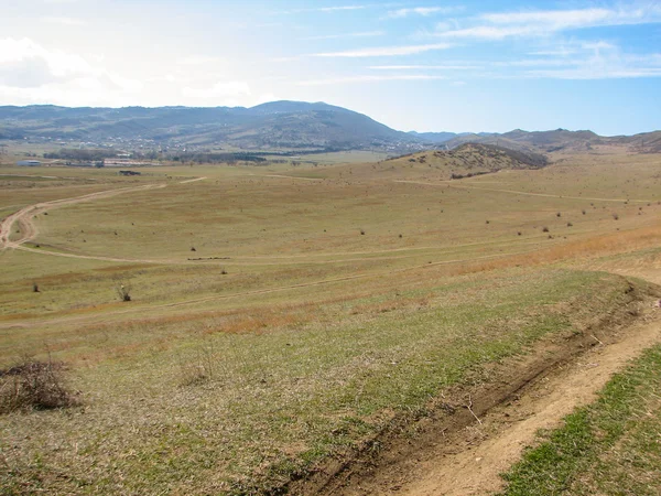 Açık mavi gökyüzü altında sarı çim kaplı tepe