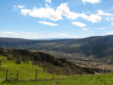 Açık mavi gökyüzü altında sarı çim kaplı tepe