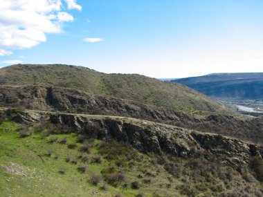 Açık mavi gökyüzü altında sarı çim kaplı tepe