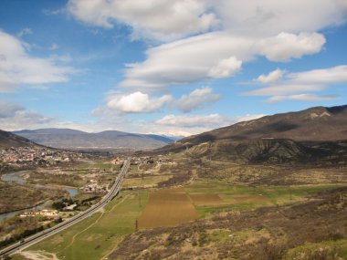 Açık mavi gökyüzü altında sarı çim kaplı tepe
