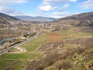 Açık mavi gökyüzü altında sarı çim kaplı tepe