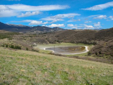 Açık mavi gökyüzü altında sarı çim kaplı tepe