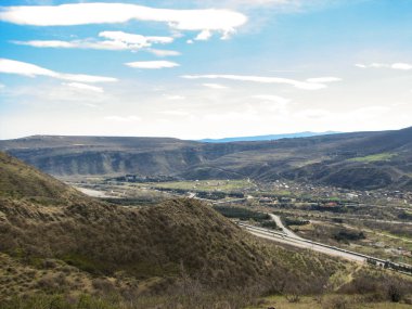 Açık mavi gökyüzü altında sarı çim kaplı tepe
