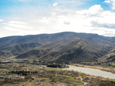 Açık mavi gökyüzü altında sarı çim kaplı tepe