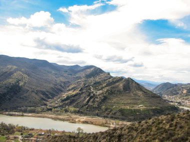 Açık mavi gökyüzü altında sarı çim kaplı tepe