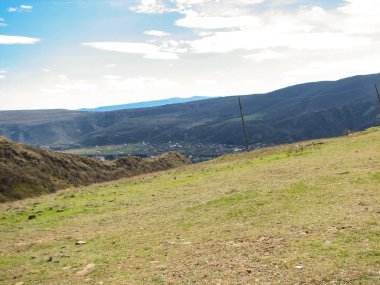 Açık mavi gökyüzü altında sarı çim kaplı tepe