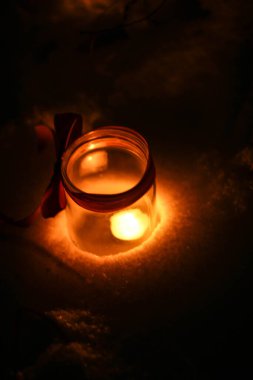 Karanlıkta bir kavanozda küçük bir mum yanar. Arka planda Bokeh ışıkları kırmızı kurdele, bokeh, bulanık arkaplan, metin için yer