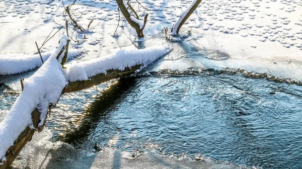 Śnieg pada na rzekę ze śnieżnymi brzegami — Zdjęcie stockowe
