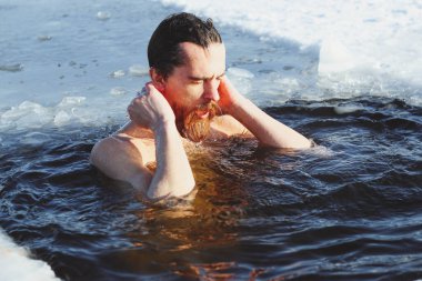 Genç, zayıf, yakışıklı, kızıl sakallı, uzun saçlı, siyah şortlu, kışın buz gibi sulara dalan Ukrayna, Shostka