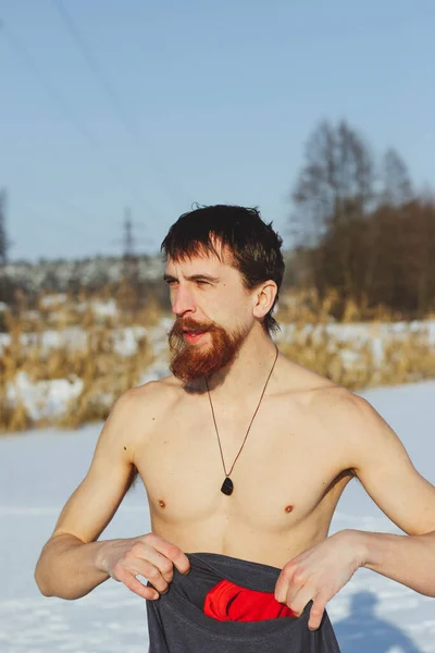 若いです スリムです ハンサムです 赤いひげと長い髪を持つスポーティ男 氷の水で泳ぐ後にダイビング 冬に氷の冷たい水に晴れた霜の日に ウクライナを背景に ショスタカ — ストック写真