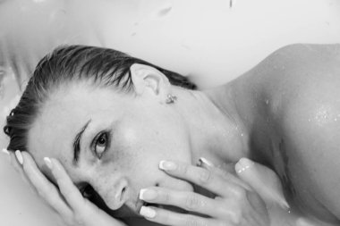 Güzel bir kız banyoda, çiçekli, yapraklı, sütlü suyla uzanıyor, narin bir genç kadın, açık arkaplan fotokopisinde şehvetli bir şekilde poz veriyor.