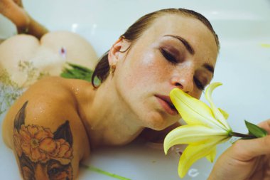 Çekici çıplak kız portresi. Süt, sarı çiçekler ve yapraklarla banyo yapıyor. Spa vücut bakımı. Şefkat, güzellik ve özen. Dinlenme ve rahatlama zamanı..