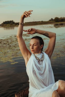 Güzel bir genç kadının portresi, çilli ve yeşil gözlü. Güzel bir gün batımı ışığı. Atletik cisim, bir teknede, suyun arka planında.