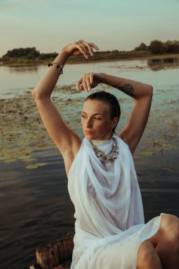 Güzel bir genç kadının portresi, çilli ve yeşil gözlü. Güzel bir gün batımı ışığı. Atletik cisim, bir teknede, suyun arka planında.