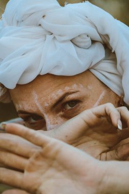 close up portrait of beautiful young sensual sexy woman with a turban on her head and jewelry and african ornaments makeup, expressive eyes on a sunny day at sunset in a tropical hot sandy beach