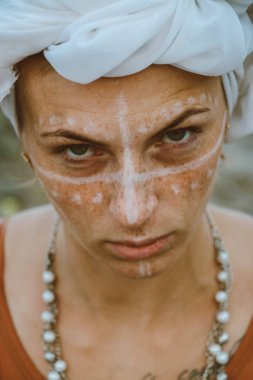 close up portrait of beautiful young sensual sexy woman with a turban on her head and jewelry and african ornaments makeup, expressive eyes on a sunny day at sunset in a tropical hot sandy beach