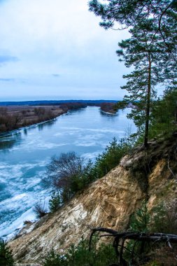Buz ve karla kaplı donmuş nehir, üst manzara. Çam ağaçlı Sandy Hill. Kış ormanı ve nehir, karlı doğa. Kış dondurucu soğuk. güzel buz dokusu