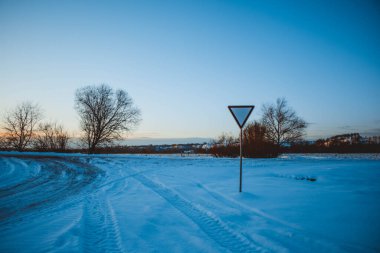 Güzel kış manzarası, bulutlu gün batımı, uzaktaki orman, kardaki tarla ve ağaçlar, dondurucu güneşli bir akşam, Ukrayna