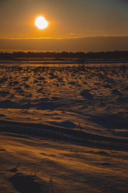 Güzel kış manzarası, bulutlu gün batımı, uzaktaki orman, kardaki tarla ve ağaçlar, dondurucu güneşli bir akşam, Ukrayna