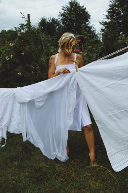 Kurutulmuş çamaşır. Genç ve güzel bir kadın, güneşli bir günde elbiselerini yıkar ve dışarı asar..