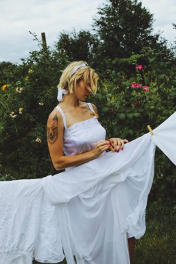 Kurutulmuş çamaşır. Genç ve güzel bir kadın, güneşli bir günde elbiselerini yıkar ve dışarı asar..