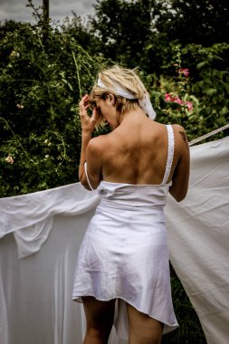 Kurutulmuş çamaşır. Genç ve güzel bir kadın, güneşli bir günde elbiselerini yıkar ve dışarı asar..