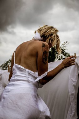 Kurutulmuş çamaşır. Genç ve güzel bir kadın, güneşli bir günde elbiselerini yıkar ve dışarı asar..