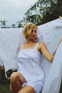 Kurutulmuş çamaşır. Genç ve güzel bir kadın, güneşli bir günde elbiselerini yıkar ve dışarı asar..