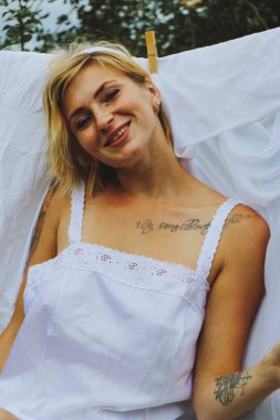 Kurutulmuş çamaşır. Genç ve güzel bir kadın, güneşli bir günde elbiselerini yıkar ve dışarı asar..